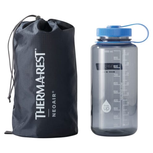 ihoppackad Therm-a-Rest NeoAir Venture uppblåsbart liggunderlag brevid en flaska