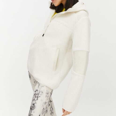 Röhnisch Wazzi Pile Hoodie, på en brunhårig modell som står åt sidan