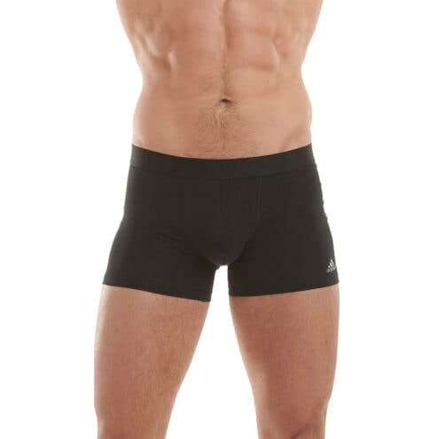 En modell har på sig Adidas Trunk 3-pack boxers (herr) och står mot kameran