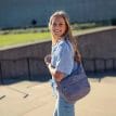 en lila Osprey Daylite Crossbody Pouch axelväska (unisex) på en modell