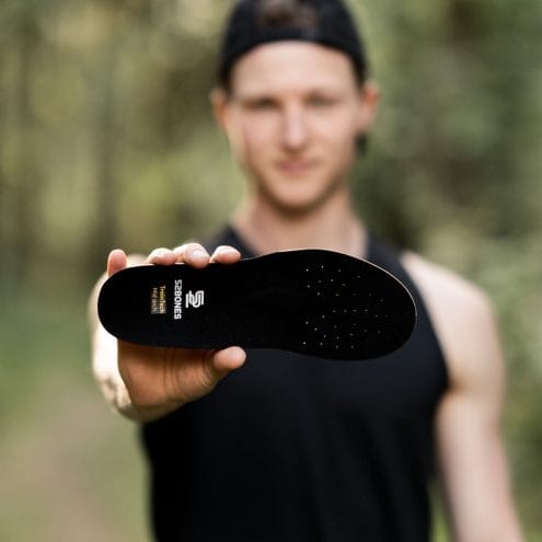 en person håller en 52Bones TrainTech uppbyggda sulor Mid (unisex)
